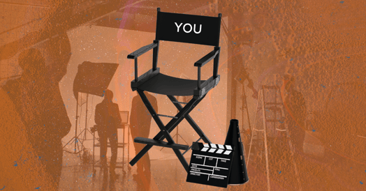 A director’s chair with “YOU” written on it and a film set in the background. 